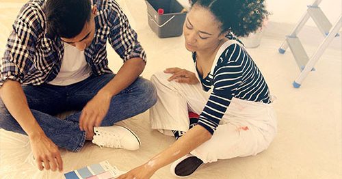Couple sitting on floor looking at paint samples, ready to do a home improvement project.