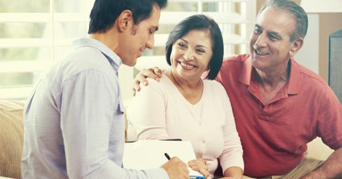 Smiling couple sits with a financial advisor discussing their retirement.