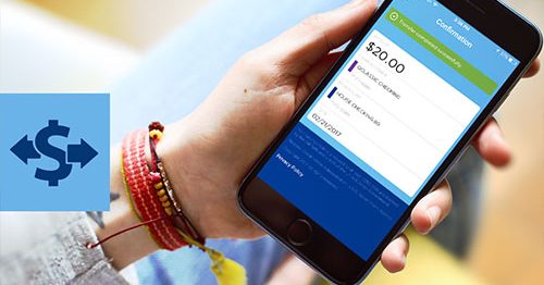Closeup of hand holding mobile device displaying Quorum mobile banking app and transfer being initiated between checking accounts.
