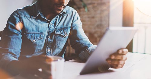 Closeup of man reviewing his tablet device, looking at his finances.