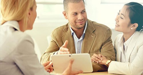 Couple sitting with bank manager discussing opening a savings account.