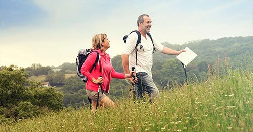 50-year-old couple hiking in mountains, smiling, and achieving work-life balance.