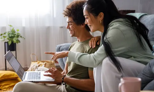 Couple opening up a free checking account online, smiling.