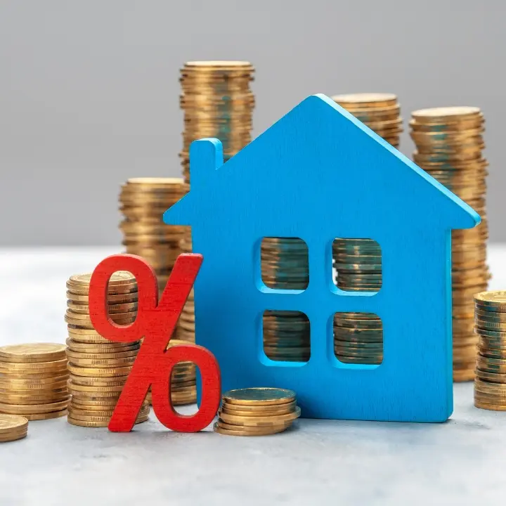 Image that illustrates the value of a home with percentage sign and house object behind a pile of dollar coins.