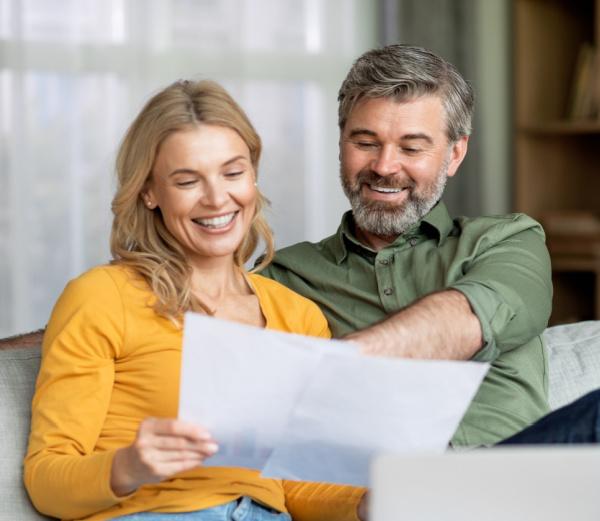 A couple looks excitedly at their financial statements that they use to build personal wealth.