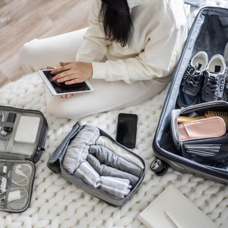 Woman with suitcase packing her valuables before a trip