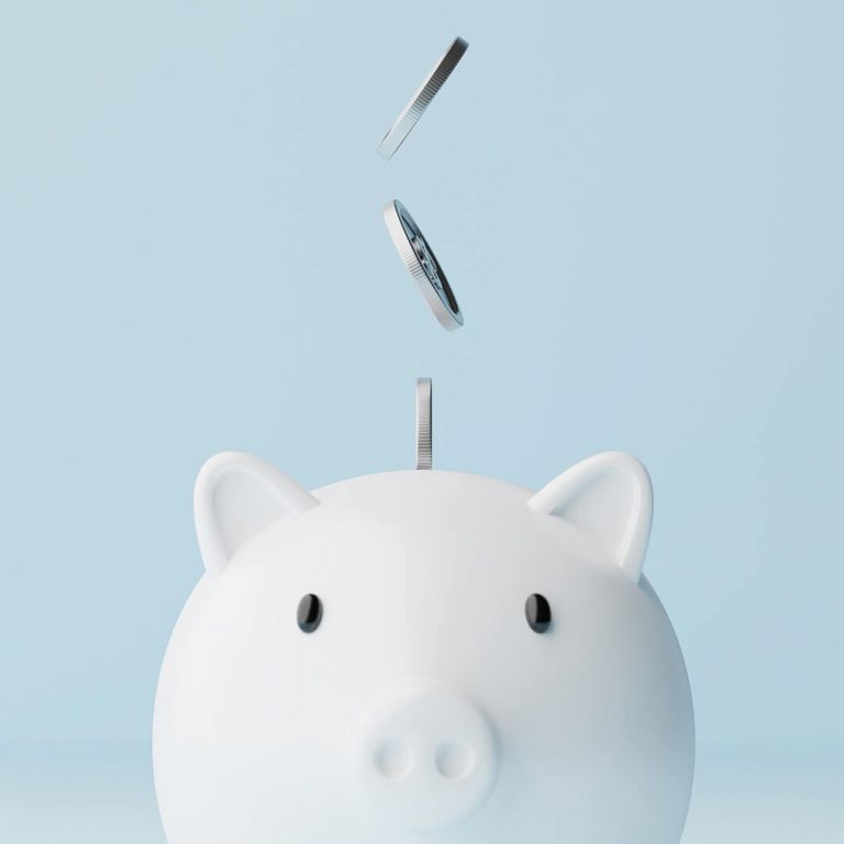 Coins falling from above into a white piggy bank (pay yourself first concept)