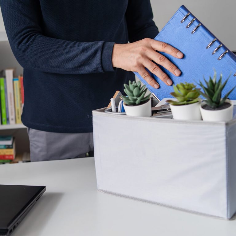 Man cleaning out his desk after a layoff and taking out a notebook to work on his finances.