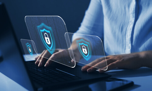 Closeup of hands at computer laptop; screen has padlock on it, illustrating cybersafety.