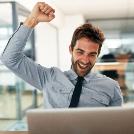 Excited man in an office, working on his computer.
