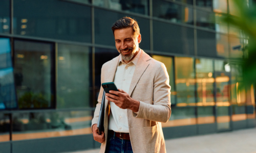 Businessman walking outside looking at mobile phone