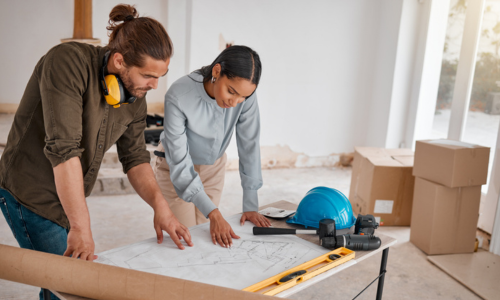 Two young people looking at building plans at home