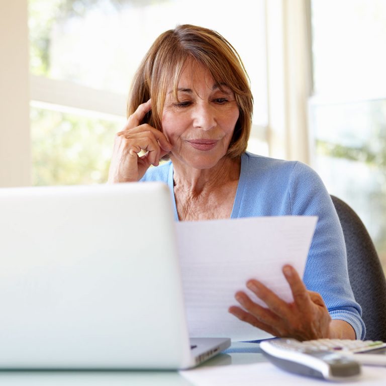 Woman reviewing her finances, sitting in front of her computer.